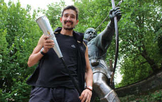 Adam Holland holds the Kenya Peace Torch beside the Robin Hood statue at Nottingham Castle, having won the 2016 Robin Hood Marathon. He is set to be the only athlete completing the 1,000km Kenya Peace Torch Relay.