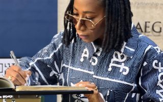 Singer-Songwriter Asa writes in the guest book at the Kigali Genocide Memorial, 2 Sept 2023